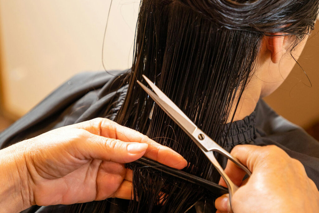 Long dark hair being combed in prep for a cut. Encinitas hair stylist Shannon.